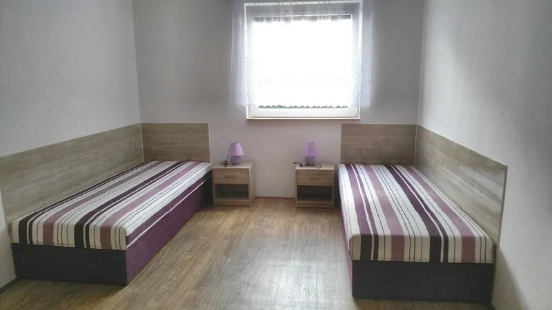 Ložnice zahradního apartmánu se dvěma postelemi a nočními stolky