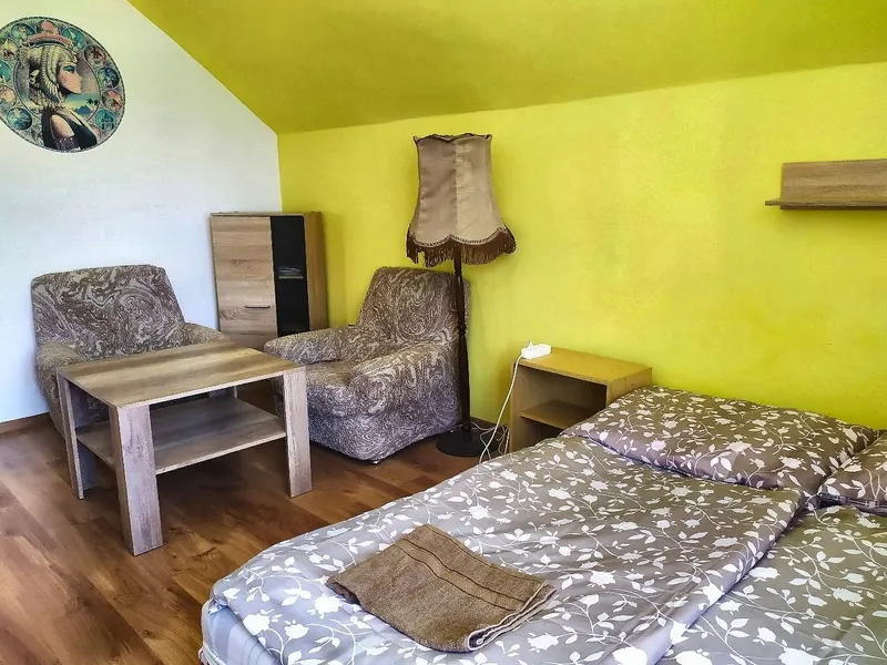 Pokoj se žlutou stěnou, manželskou postelí a křesly