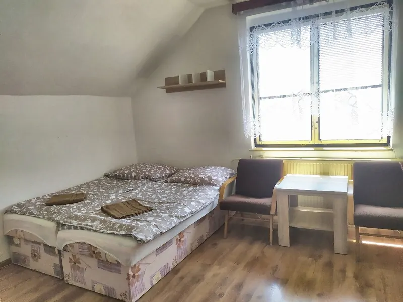 Podkrovní pokoj s postelí pod oknem